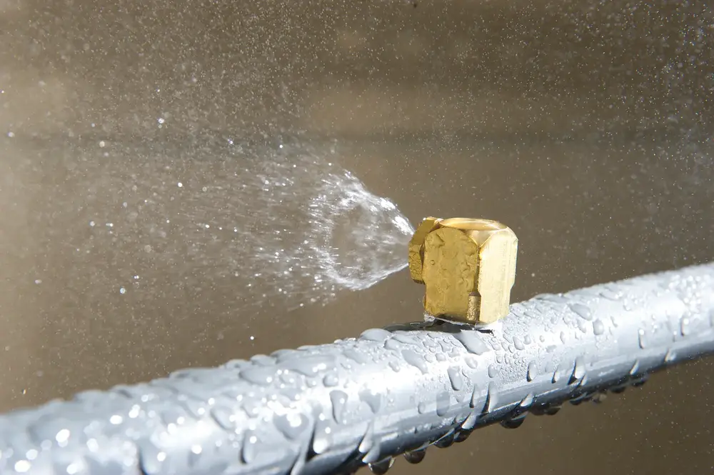 Water spraying out of grey pipe as part of wall assembly testing.