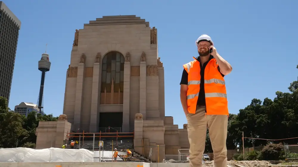 Construction worker on phone in front of stone building