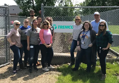 Employees smiling in front of Tremco’s company garden