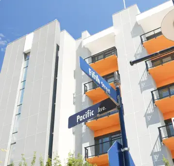 Apartment building using white and gray Dryvit panels with orange balcony on Pacific Avenue sign in the foreground