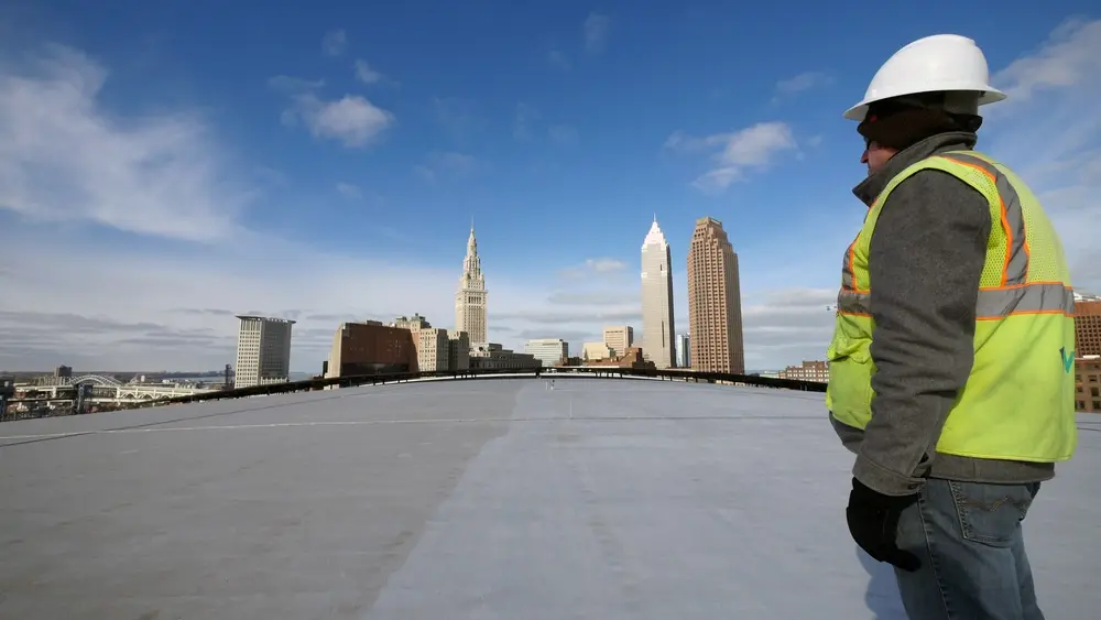 Construction worker looking at city skyline while standing on rooftop