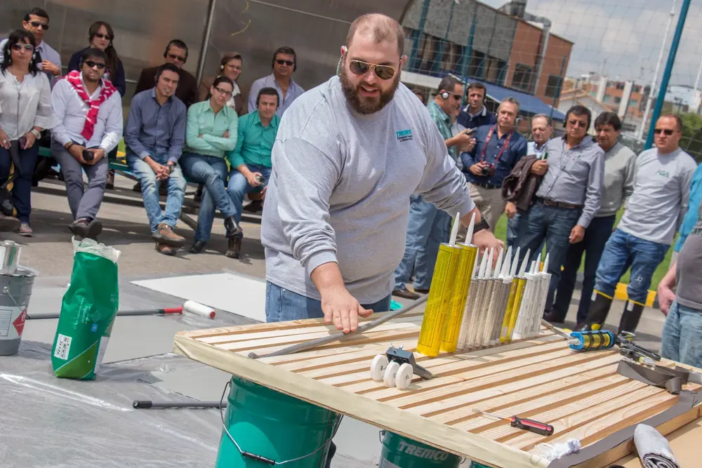 Construction worker teaching how to apply Tremco sealant at outdoor training seminar  