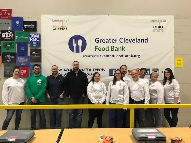 Group of Tremco employees smiling in front of Greater Cleveland Food Bank sign