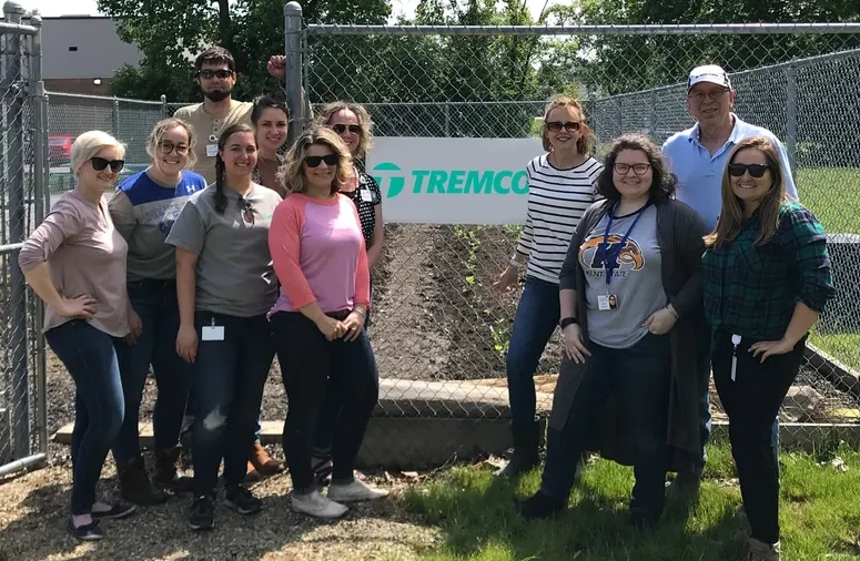 Employees smiling in front of Tremco’s company garden