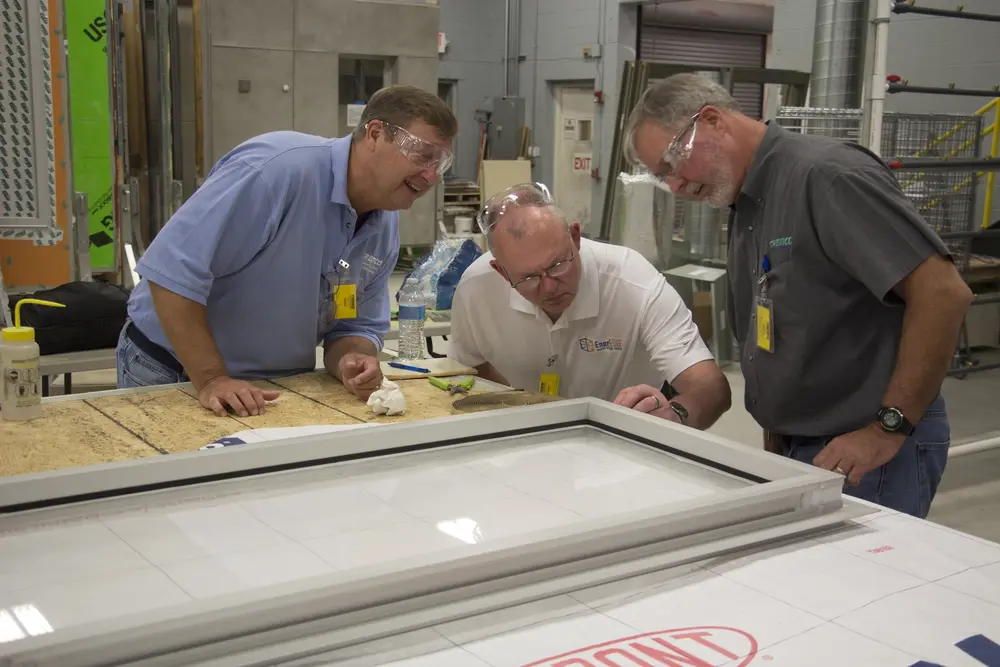 Three employees investigating window assembly in building science laboratory 