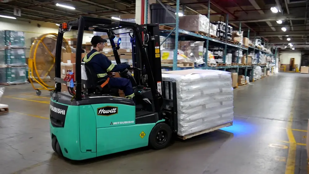 Construction worker operating forklift inside manufacturing facility 